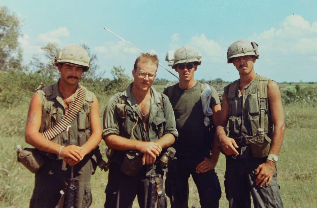 4 men in military gear with helmets and rifles